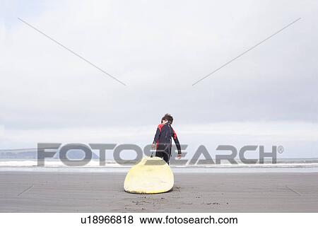 Boy pulling surfboard on beach View Large Photo Image Stock Photo - Boy pulling surfboard on beach. Fotosearch