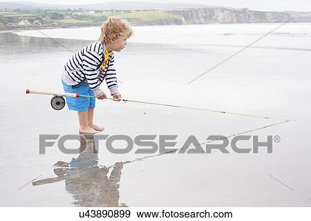 Boy standing on beach with fishing rod View Large Photo Image Stock Photo - Boy standing on beach with fishing rod. Fotosearch