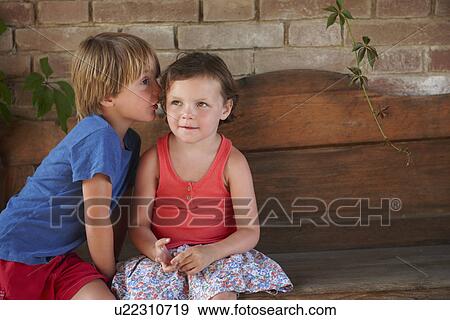 Boy whispering into girl's ear View Large Photo Image Stock Photo - Boy whispering into girl's ear. Fotosearch
