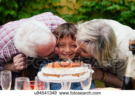 Stock Photo - Boy with birthday cake, being kissed by grandparents. Fotosearch