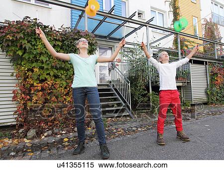 Stock Photography - Brother and sister playing with spinning tops outside house. Fotosearch