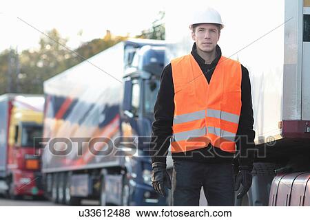 Stock Photo - Builder standing in front of truck. Fotosearch
