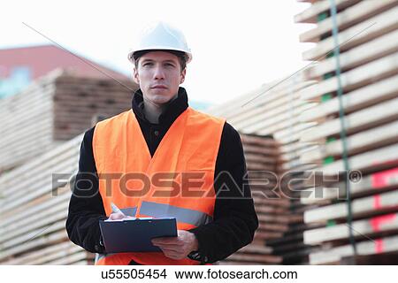 Picture - Builder writing paperwork using clipboard. Fotosearch