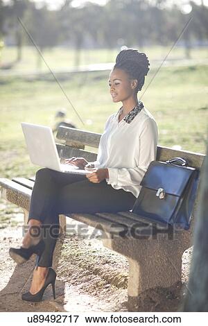 Business woman using laptop on park bench View Large Photo Image Stock Photo - Business woman using laptop on park bench. Fotosearch