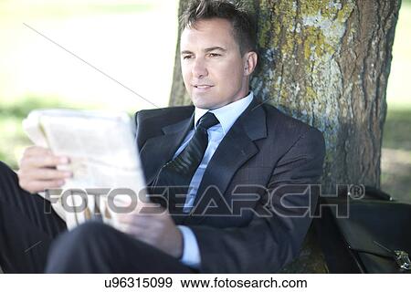 Stock Photo - Businessman reading under tree. Fotosearch