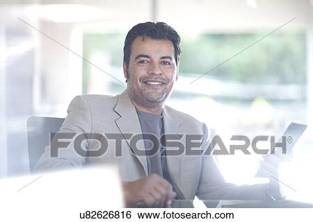 Stock Photograph - Businessman sitting at desk, using digital tablet. Fotosearch
