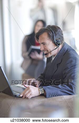 Businessman using laptop, businesswoman writing View Large Photo Image Stock Image - Businessman using laptop, businesswoman writing. Fotosearch