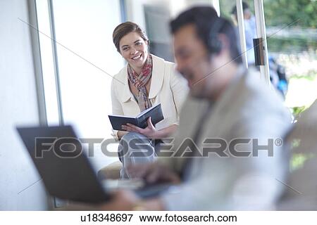 Businessman using laptop, businesswoman writing View Large Photo Image Stock Photo - Businessman using laptop, businesswoman writing. Fotosearch