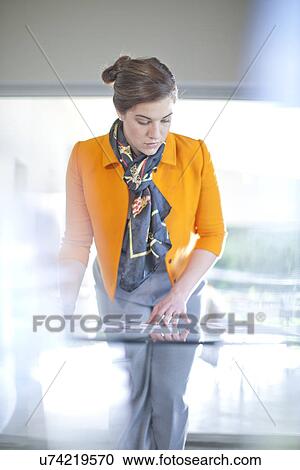 Stock Image - Businesswoman looking at paperwork on desk. Fotosearch