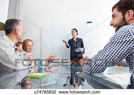 Stock Image - Businesswoman presenting to colleagues. Fotosearch