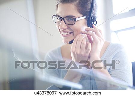 Businesswoman using laptop computer and telephone headset View Large Photo Image Stock Photo - Businesswoman using laptop computer and telephone headset. Fotosearch