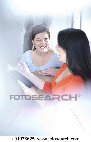 Stock Photography - Businesswomen having conversation and writing. Fotosearch
