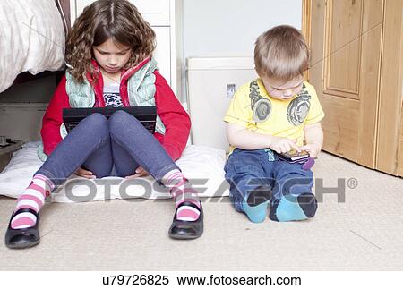 Stock Photography - Children using digital tablet and cellular phone. Fotosearch
