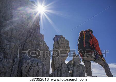 Stock Photograph - Climber looking at rocky walls, Brenta Dolomites, Italy. Fotosearch