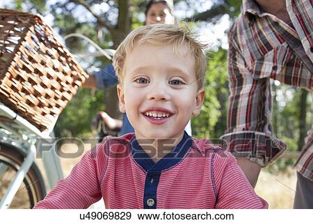 Stock Photo - Close up of boy with parents in background. Fotosearch