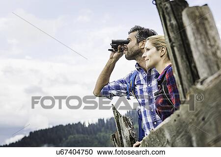 Stock Image - Close up of couple enjoying view through binoculars, Tirol, Austria. Fotosearch