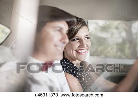 Stock Image - Close up of couple in vintage car. Fotosearch