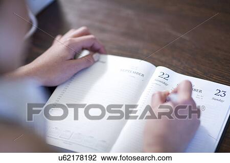 Stock Image - Close up of female writing in diary. Fotosearch