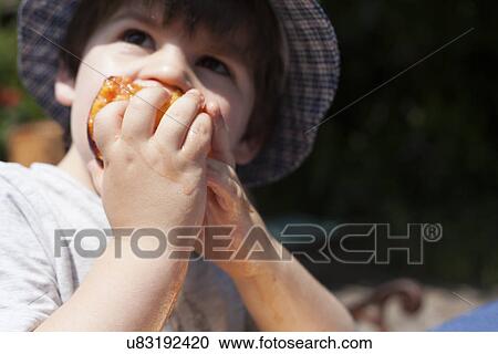 Stock Image - Close up of male toddler eating a peach. Fotosearch
