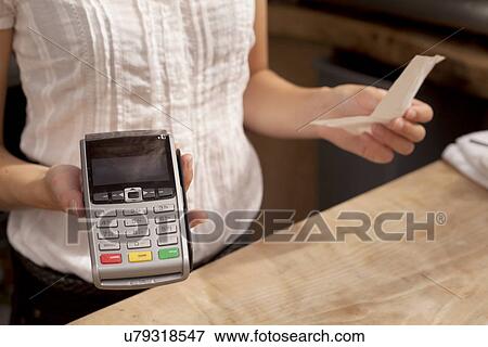 Close up of waitress holding credit card reader at kitchen counter View Large Photo Image Stock Photo - Close up of waitress holding credit card reader at kitchen counter. Fotosearch