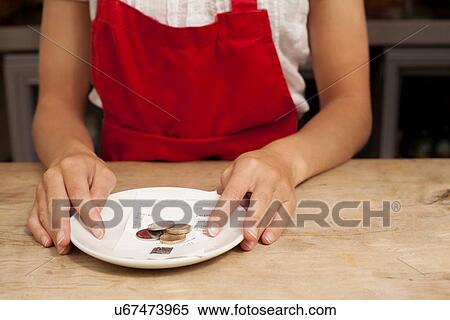 Stock Photography - Close up of waitress with bill and gratuity at kitchen counter. Fotosearch