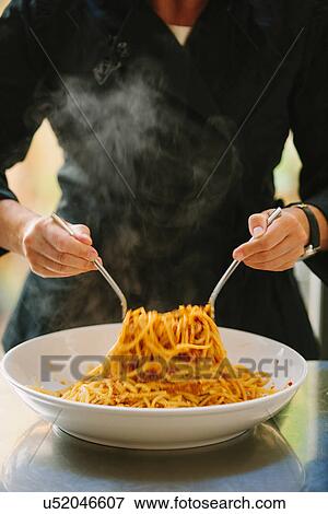 Stock Photo - Close up of woman mixing bolognese sauce with spaghetti. Fotosearch