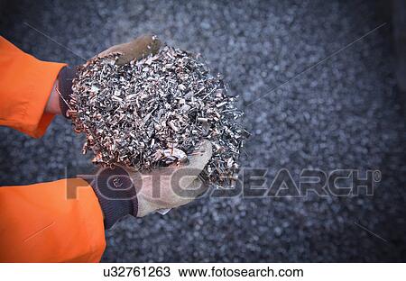 Stock Image - Close up of worker holding titanium turnings. Fotosearch