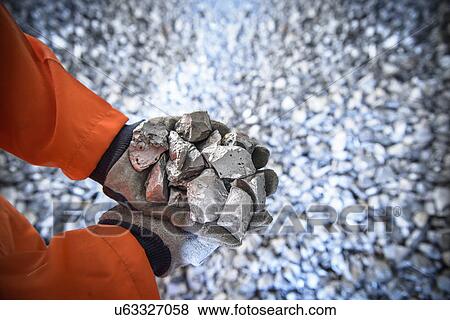 Stock Photo - Close up of workers hands holding crushed titanium. Fotosearch