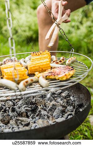 Stock Photo - Close up of young man barbecuing lunch. Fotosearch