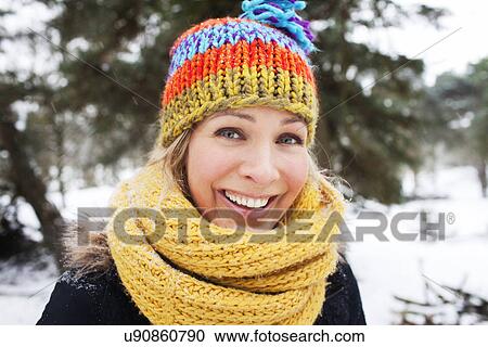 Stock Image - Close up portrait of woman in wooly hat and scarf in winter. Fotosearch