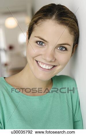 Stock Image - Close up portrait of young woman leaning against wall. Fotosearch
