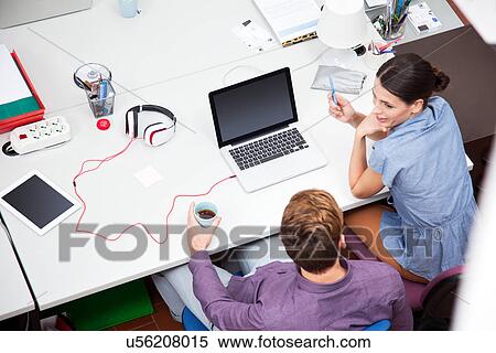 Stock Photography - Colleagues working in office, high angle. Fotosearch