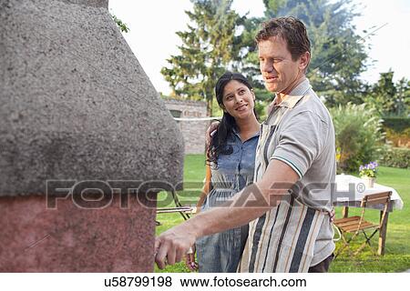 Stock Photo - Couple cooking barbecue in garden. Fotosearch