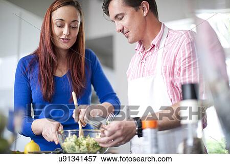 Stock Photo - Couple cooking, mixing ingredients in bowl. Fotosearch