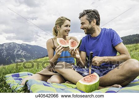 Stock Photograph - Couple eating watermelon at picnic. Fotosearch