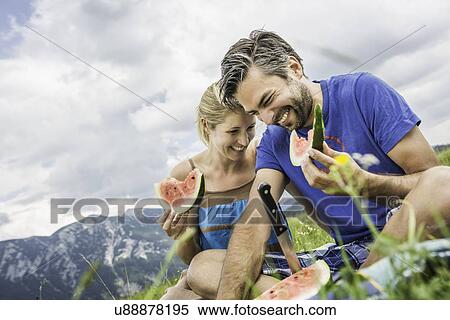 Stock Photography - Couple eating watermelon at picnic. Fotosearch