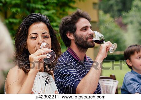 Couple enjoying red wine at family meal View Large Photo Image Stock Image - Couple enjoying red wine at family meal. Fotosearch