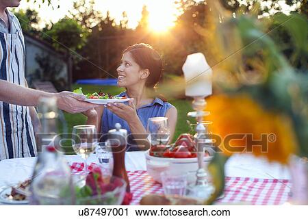 Stock Image - Couple having dinner in garden. Fotosearch