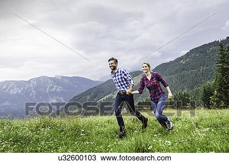 Couple holdings hands and running, Tirol, Austria View Large Photo Image Stock Image - Couple holdings hands and running, Tirol, Austria. Fotosearch