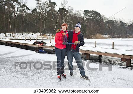 Stock Image - Couple ice skating, holding hands. Fotosearch