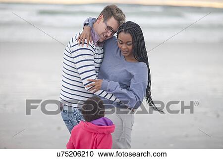 Couple in embrace with child on beach View Large Photo Image Stock Image - Couple in embrace with child on beach. Fotosearch
