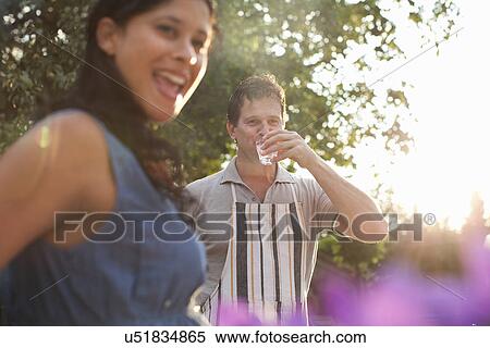 Couple in garden, man drinking glass of water View Large Photo Image Stock Photography - Couple in garden, man drinking glass of water. Fotosearch