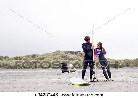 Couple on beach, woman leaning on surfboard View Large Photo Image Stock Photograph - Couple on beach, woman leaning on surfboard. Fotosearch