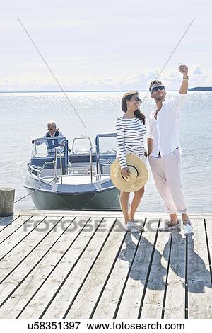 Couple photographing themselves on pier, Gavle, Sweden View Large Photo Image Stock Photo - Couple photographing themselves on pier, Gavle, Sweden. Fotosearch