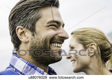 Stock Photo - Couple smiling and looking at opposite directions. Fotosearch