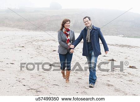 Stock Image - Couple walking on beach, Thurlestone, Devon, UK. Fotosearch