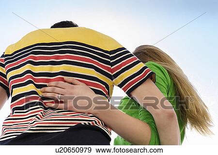 Couple with arms around each other against sky, low angle View Large Photo Image Stock Photo - Couple with arms around each other against sky, low angle. Fotosearch