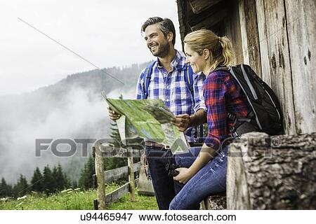 Stock Photo - Couple with map embarking on trek, Tirol, Austria. Fotosearch