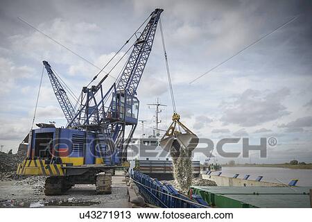 Stock Image - Crane loading recycled glass onto ships. Fotosearch