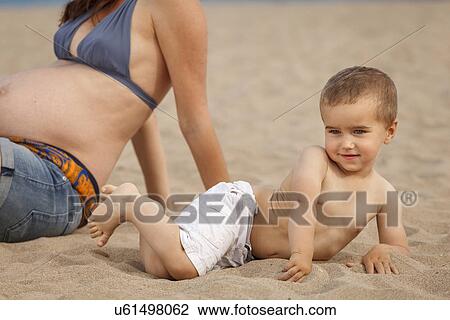 Cropped image of pregnant mother and son lying on beach View Large Photo Image Stock Image - Cropped image of pregnant mother and son lying on beach. Fotosearch
